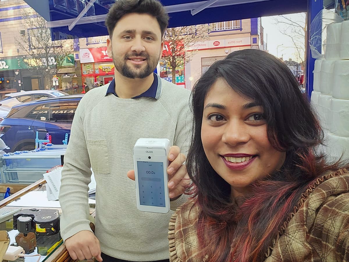 Happy with the owner of a phone and electronics shop, card terminal in hand